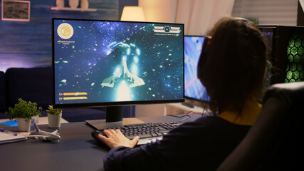 Player sitting on gaming chair and start playing space shooter video game wearing professional headset. Modern studio equipped with RGB system desktop, keyboard, mouse, using technology network
