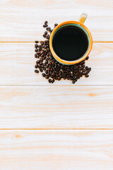 Cup of coffee and coffee beans on wooden background, top view, copy space