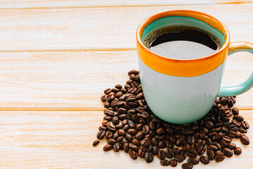 Cup of coffee and coffee beans on wooden background