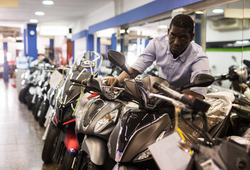 Portrait of adult man buying new motorcycle at modern showroom. High quality photo