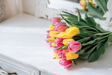 Reflection of Fresh spring yellow and pink tulips bouquet on white wood table background in mirror with copy space for text. Love, easter, International Women, Mother and Happy Valentine day concept