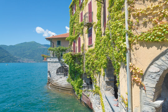 View of the famous Lake Como from the small village named Nasso, Italy. Green ivy on a building in the foreground.
