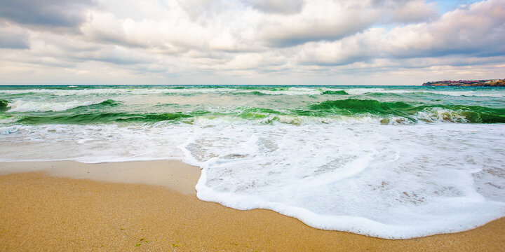 sea tide on a cloudy sunset. green waves crashing golden sandy beach. storm weather approaching. summer holiday concept