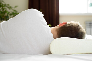A man is resting on an orthopedic pillow. The concept of taking care of your health. Healthy sleep,...