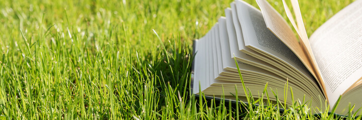 Open book lies on a lawn in the garden. Holidays and relaxation in the garden during coronavirus...