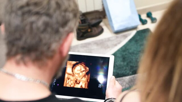 A couple using a tablet looking at pregnant woman ultrasound