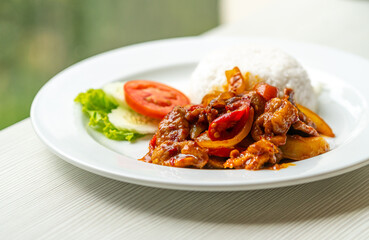 Stir-fried pork with traditional Thai Chili Paste or Moo Pad Prickpow in Thailand language with white jasmine rice, natural light from the window.