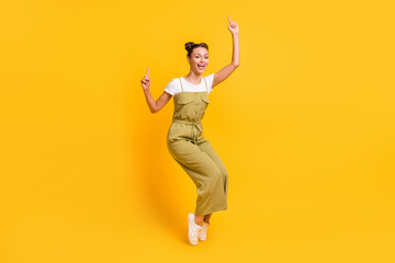 Full size photo of optimistic brunette lady dance wear bright t-shirt overall sneakers isolated on yellow color background