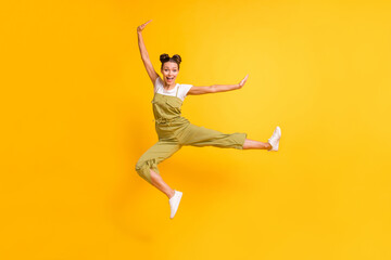 Photo of excited funny fighter lady jump kick leg wear green overall footwear isolated yellow background