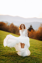Fototapeta na wymiar Bride in wedding dress runing at sunset in the mountains