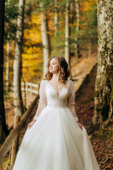 Obraz na płótnie Canvas Beautiful bride with wavy hair walks on a trail in autumn park.