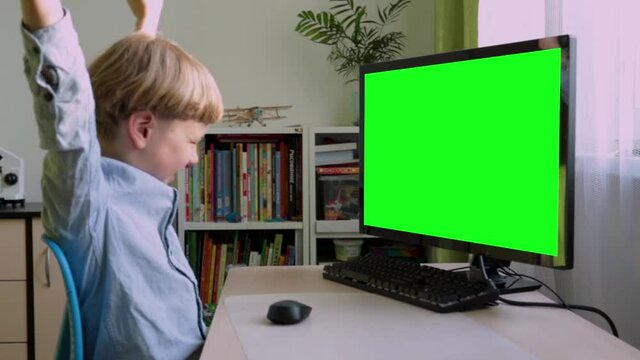 A school-age boy is studying at the computer, preparing for school in the first grade.