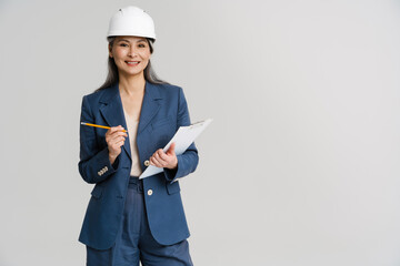 Asian smiling woman wearing helmet posing with clipboard and pencil
