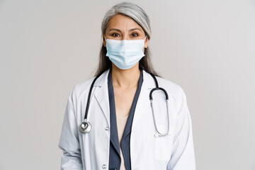 Asian mature woman in uniform and protective mask looking at camera