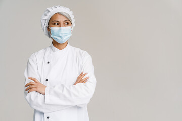 Asian mature woman in white chef uniform and face mask posing at camera