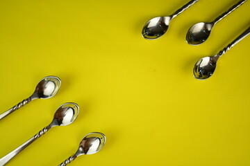 silver ware sppon on bright yellow background