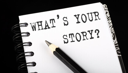 WHAT'S YOUR STORY written text in a small notebook on a black background
