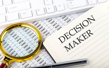 DECISION MAKER text on notebook with chart, magnifier,keyboard and pen