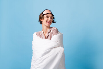 Photo of lovely attractive woman wrapped in blanket look empty space good mood isolated on blue color background