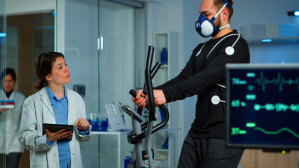 Performant sportsman measuring heart rate with performant ekg equipment in sports science...