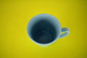 blue cup of coffee on bright yellow background