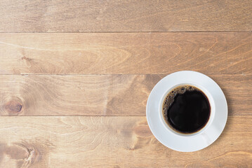 Top view, Hot black coffee in a white cup with saucers on a wooden table. Space for your text..