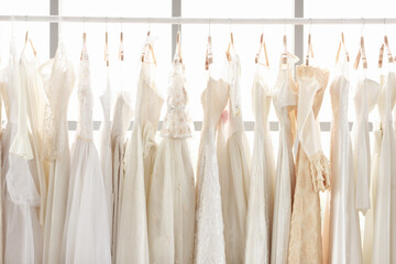 Assortment of dresses hanging on a hanger on the background studio. Many beautiful wedding dresses hang in the store. Concept Luxury bridal gowns shop.