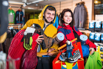 Man and woman demonstration new tourist equipment in sports clothes store.