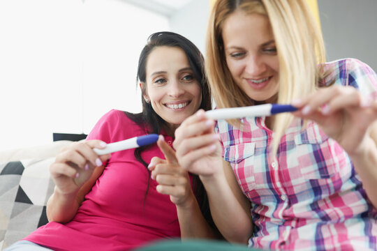Two young happy women looking at pregnancy test