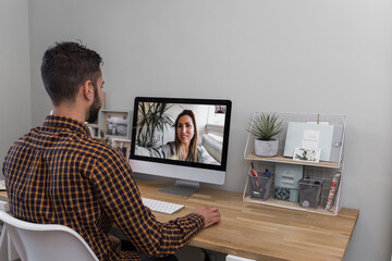 man makes a video call with a woman, dark-haired man with a beard and plaid shirt makes a video call with a woman from the computer