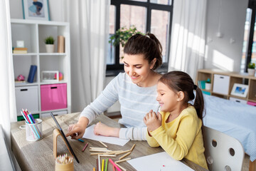 family, motherhood and leisure concept - mother spending time with her little daughter drawing with...