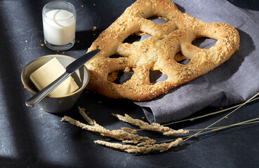 food, baking and cooking concept - close up of cheese bread, butter in bowl, knife and glass of milk on kitchen table