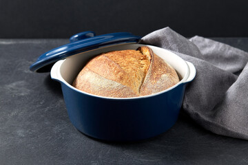 food and cooking concept - homemade craft bread in ceramic baking dish on table