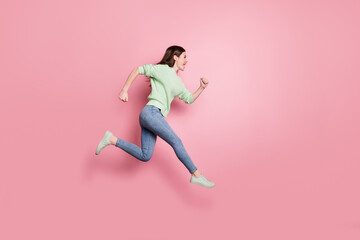 Fototapeta na wymiar Full size profile photo of brunette nice girl jump run yell wear lime sweater jeans sneakers isolated on pink color background