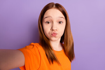 Self-portrait of beautiful trendy funky girl sending air kiss good mood isolated over violet purple...