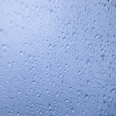 Water rain drops on blue glass surface as background. Abstract backdrop.