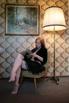 Eine Frau liest ein Buch unter einem altmodischen Wandgemälde