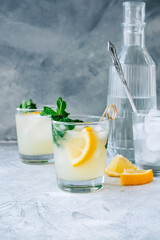Ice lemonade in glass with lemon pieces, fresh mint and ice cubes.