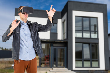 Cheerful man in virtual glasses in front of new house