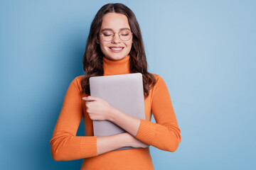 Photo of peaceful woman hug tablet closed eyes dream posing on blue background