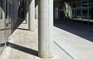 Pedestrian street among two glass wall with a concrete colonnade. Tiled pavement. Background for copy space.