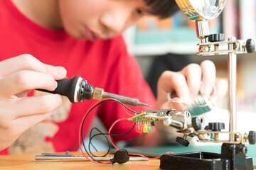 STEM education and 21st century skills concept. Young Asian teenager, kid is soldering water...