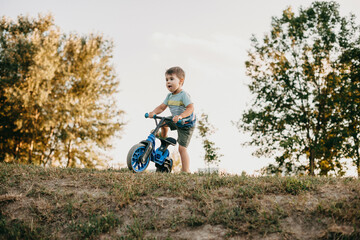 Caucasian boy riding the bike on a hill during summer walk in the countryside