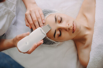 Fototapeta premium Top view photo of a caucasian woman lying while having professional spa procedures with apparatus at the salon
