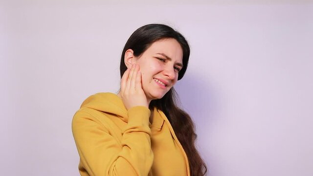 The woman has a sore ear - infection, inflammation from infection and otitis. Arthritis temporal lower jaw joint, osteoarthritis and pain in the jaw.