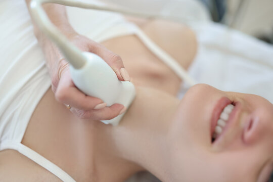 Doctor conducts ultrasound examination of thyroid gland of woman