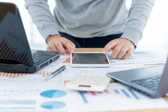 Businessman hand holding tablet working to analysis business data, finance document with laptop computer on desks, concept,