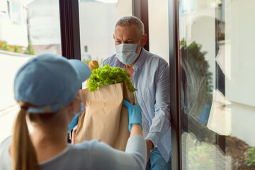 Delivery service girl brings groceries to an elderly man during the COVID pandemic. Everybody...