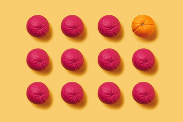Unique orange among many pink ones against pastel orange background. Minimal summer organic fruit...