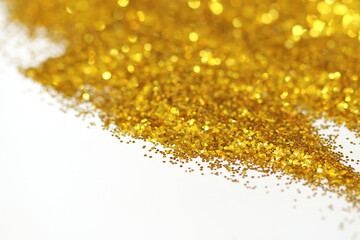 Golden glitter sand texture handful spread on white, abstract background with copy space.